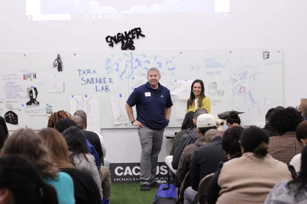 Participants at PPC 2024 engaging in a session at TXRX Labs, with presenters discussing career pathways and strategies for workforce readiness, surrounded by visual aids on a whiteboard.