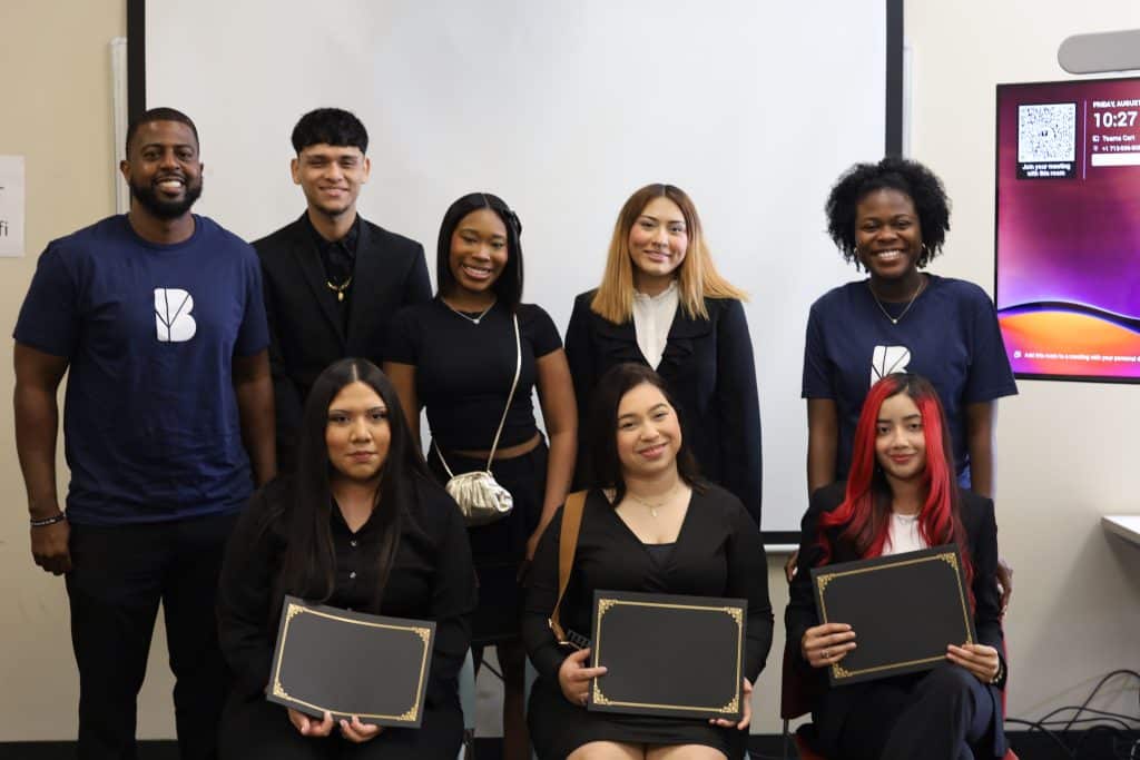 Group of students celebrating completion of BridgeYear's Career Cohorts program, holding certificates, in a classroom setting with a presentation screen.