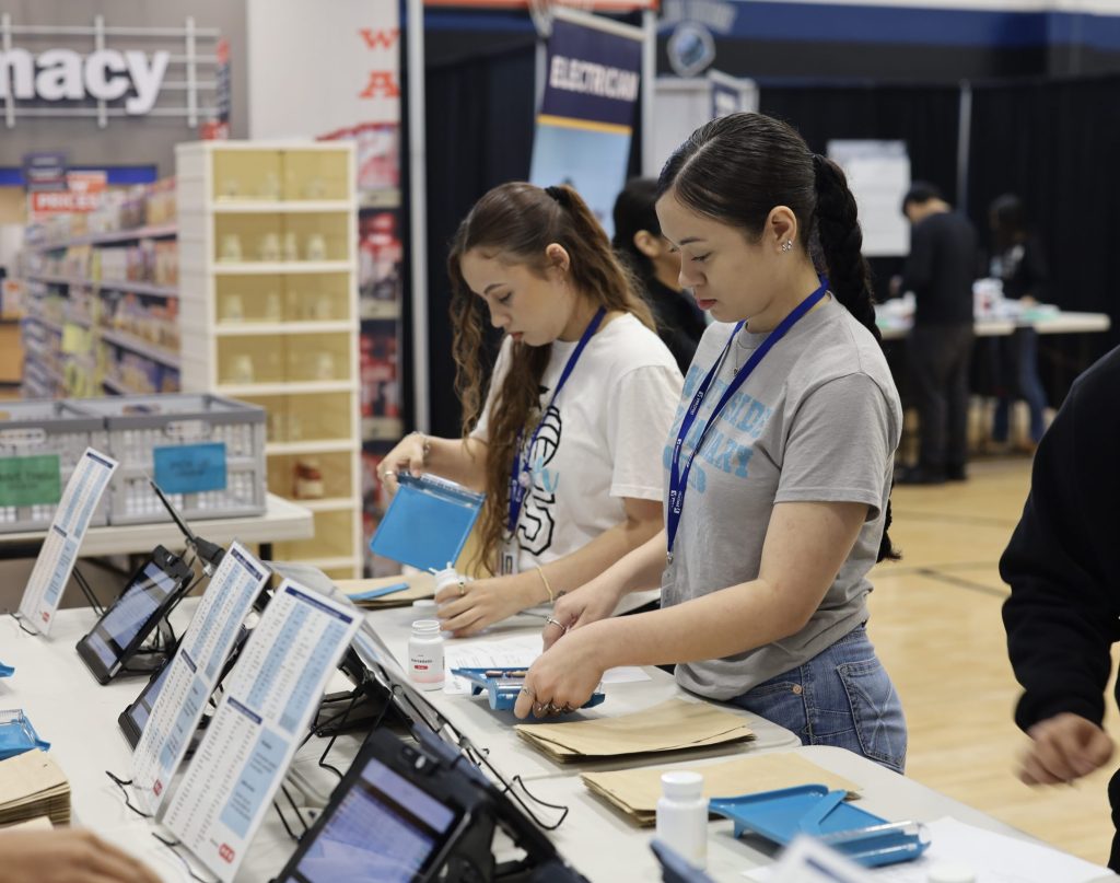 Students engaged in hands-on activities at a career exploration event, working with tablets and materials to learn about pathways to success in high-demand careers, supporting BridgeYear's mission for underserved youth in Houston.