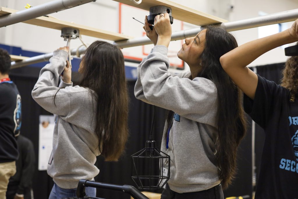 Students engaging in hands-on skills training, assembling equipment in a career exploration program setting, emphasizing practical learning for future career pathways.